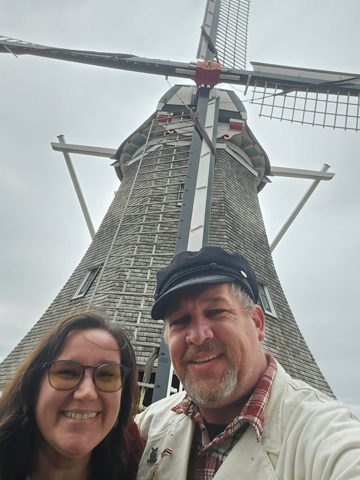 a couple standing in front of a dutch windmill