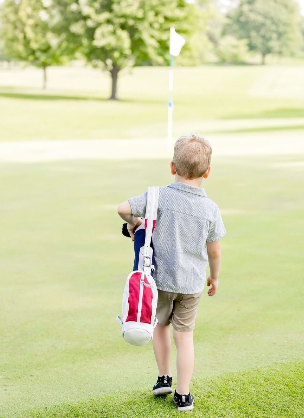 child on a golf green with a charlie golf co bag